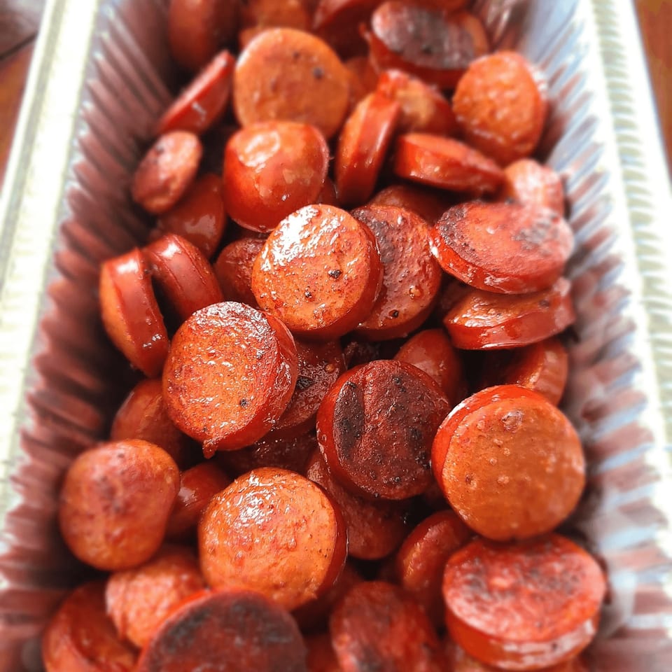 Close-up of sliced, grilled sausage pieces in a foil pan, ready to serve at Stuboy's BBQ.