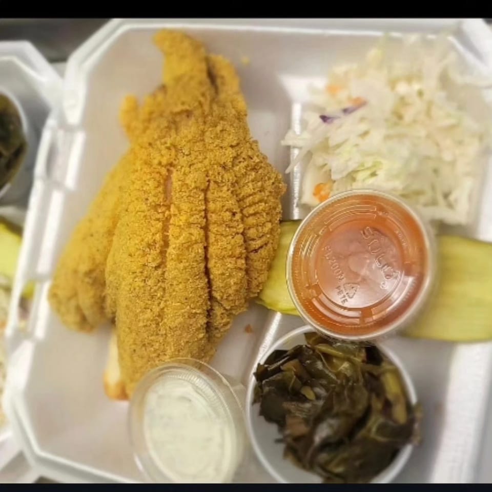 Fried catfish, coleslaw, collard greens, and sauces in a takeout container from Stuboy's BBQ.