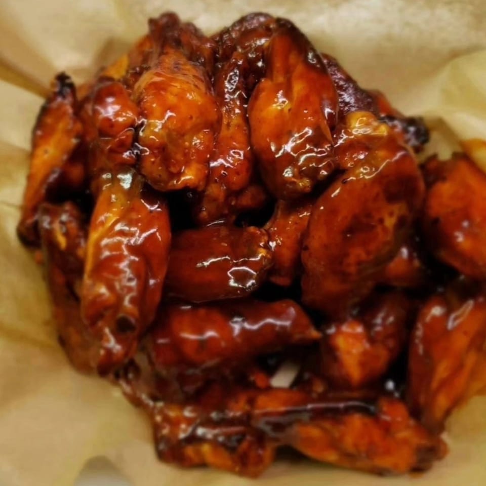 A close-up of Stuboy's BBQ chicken wings, glistening with a rich, dark sauce.