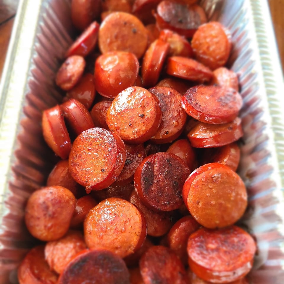 Close-up of glistening, sliced Stuboy's BBQ sausage in a foil pan, ready to serve.